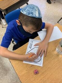 elementary school student drawing on a card for veterans day