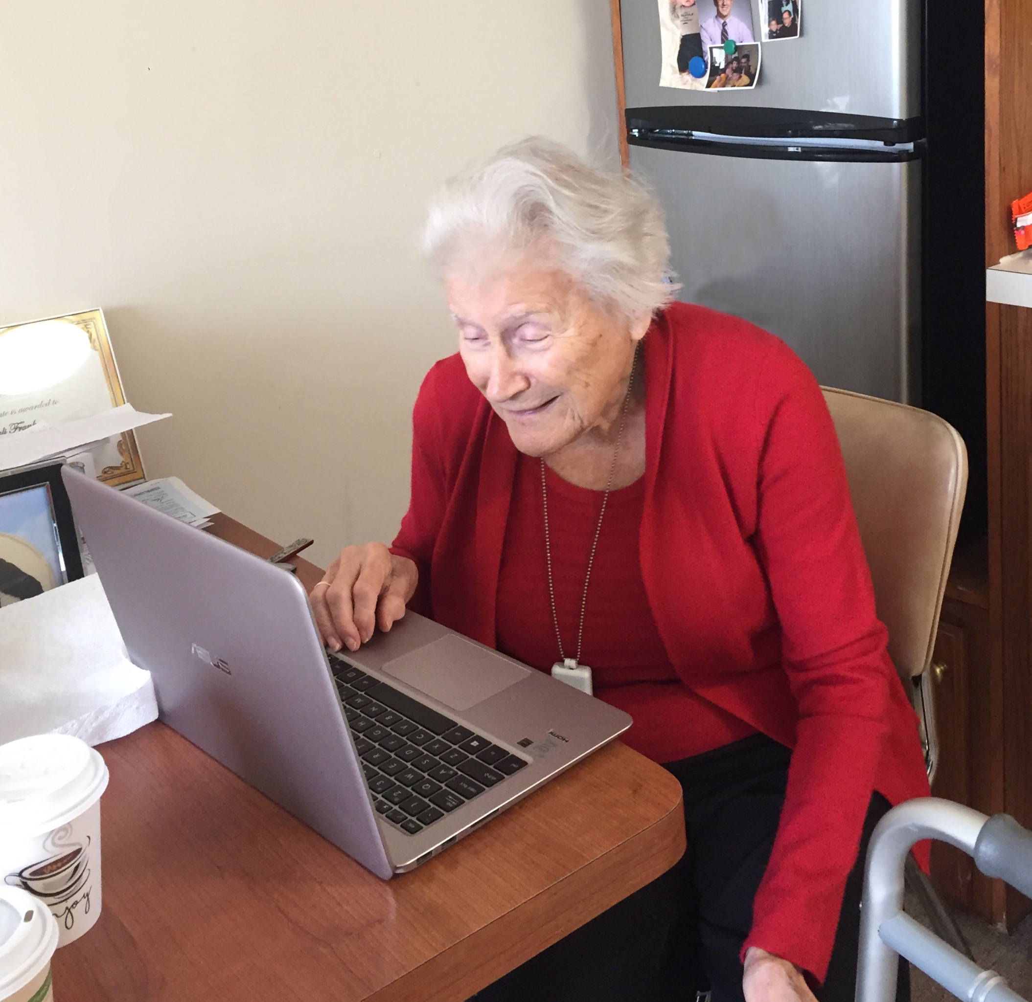 older woman smiling and looking at a laptop screen