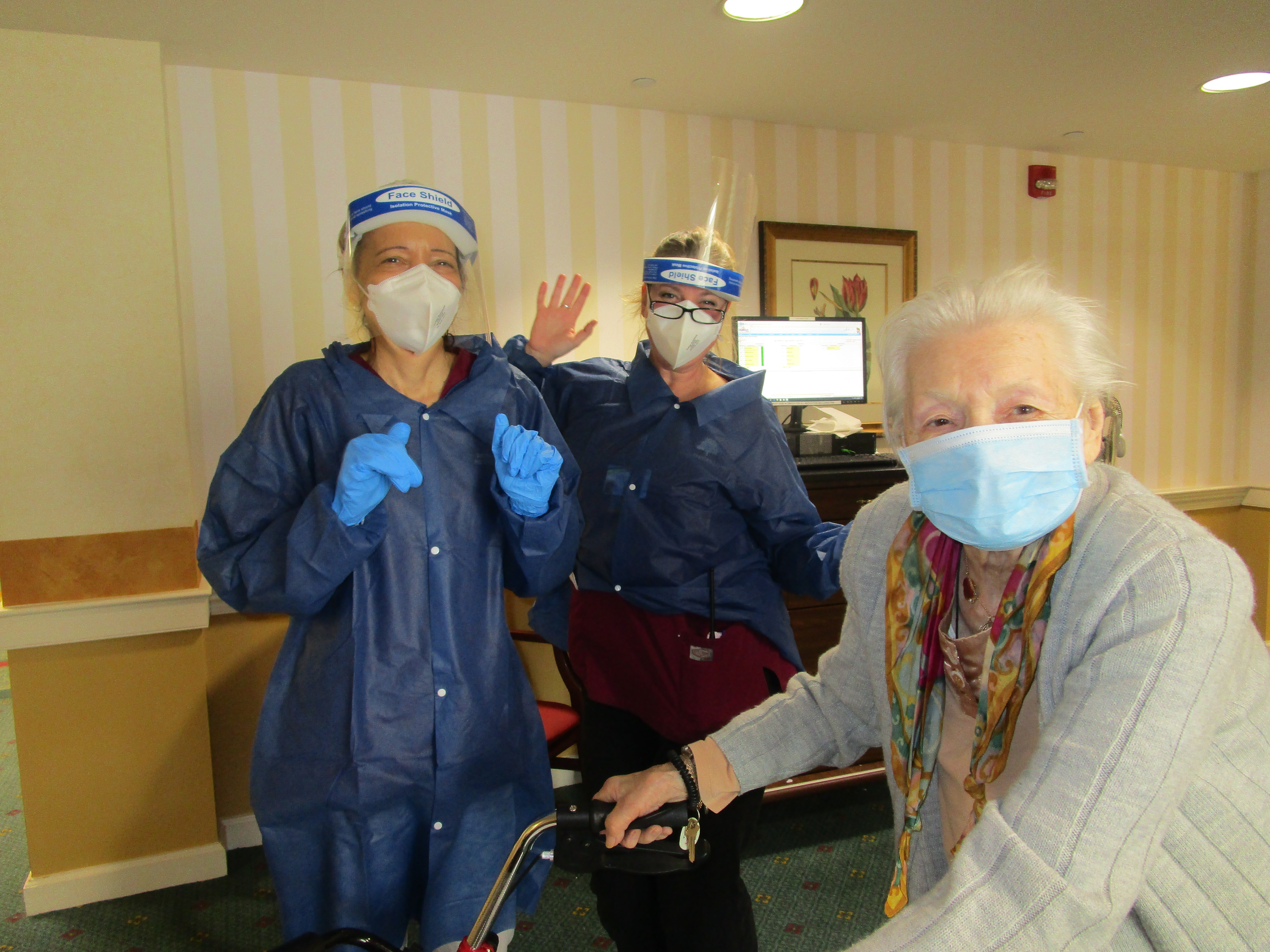 three women, wearing masks, waving at camera