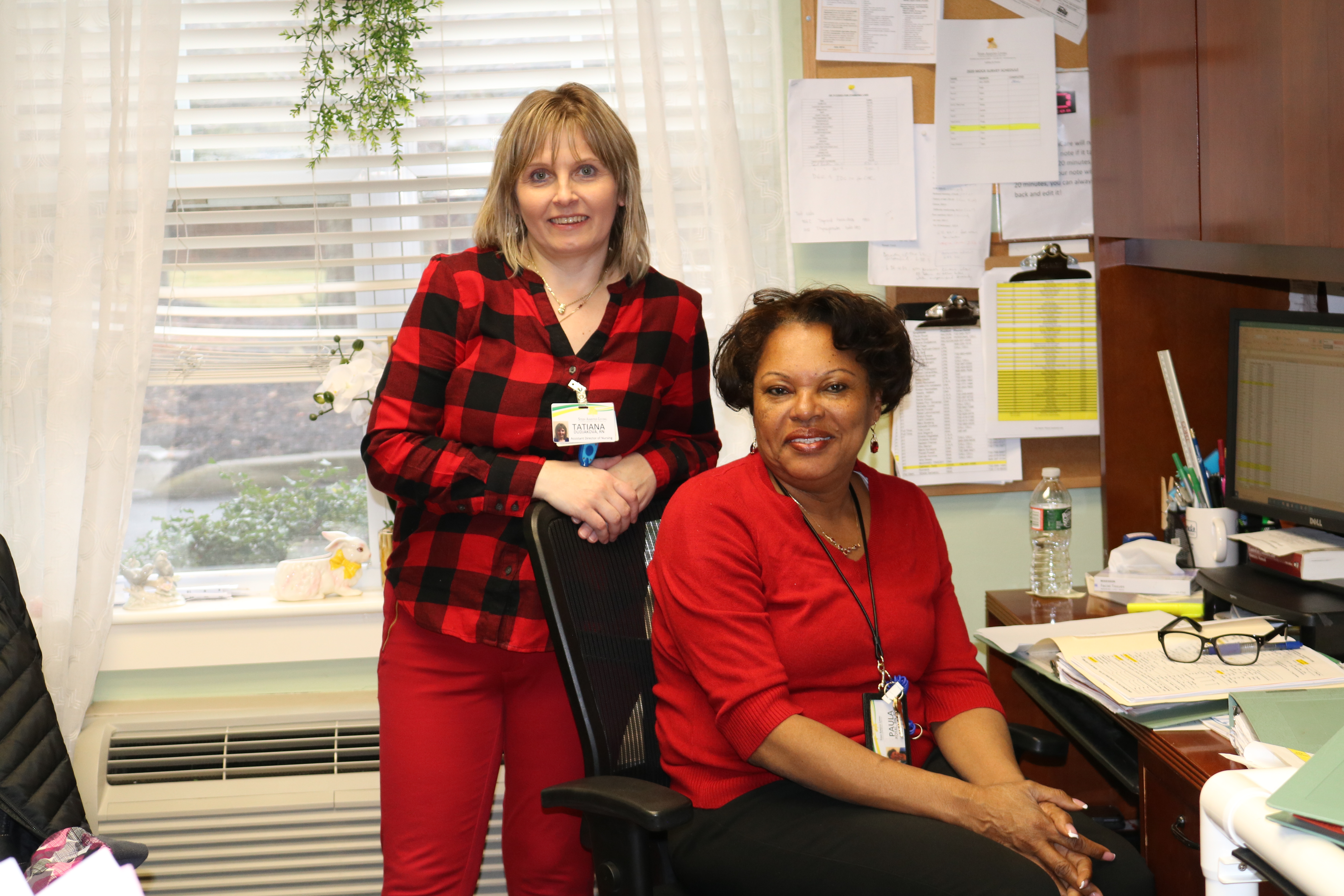 two women, one standing, one sitting, posing for camera