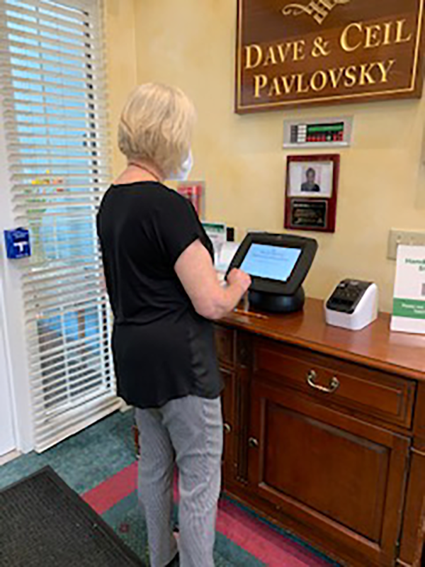 woman using touch screen sign-in kiosk