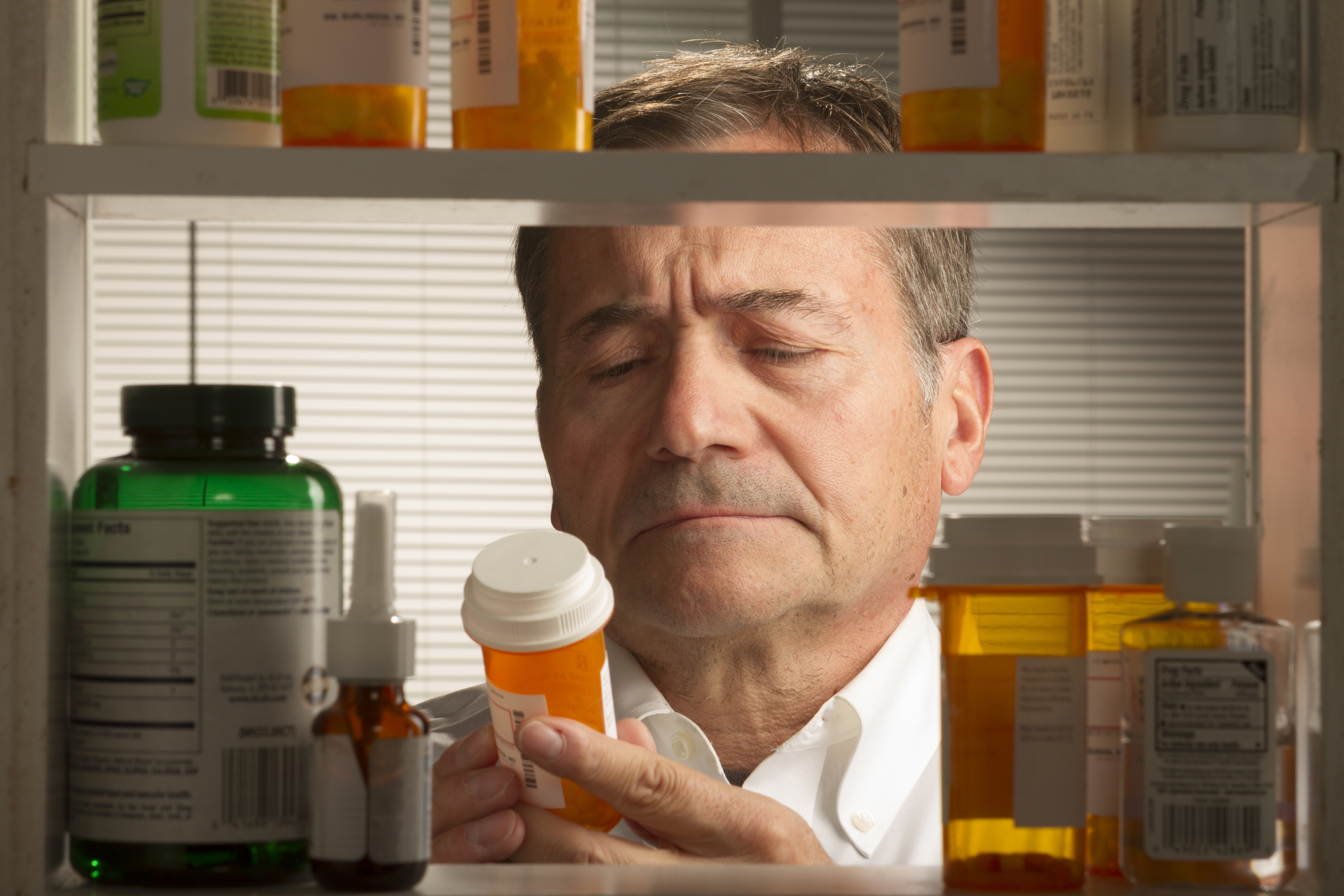 older man looking at medicine bottle label