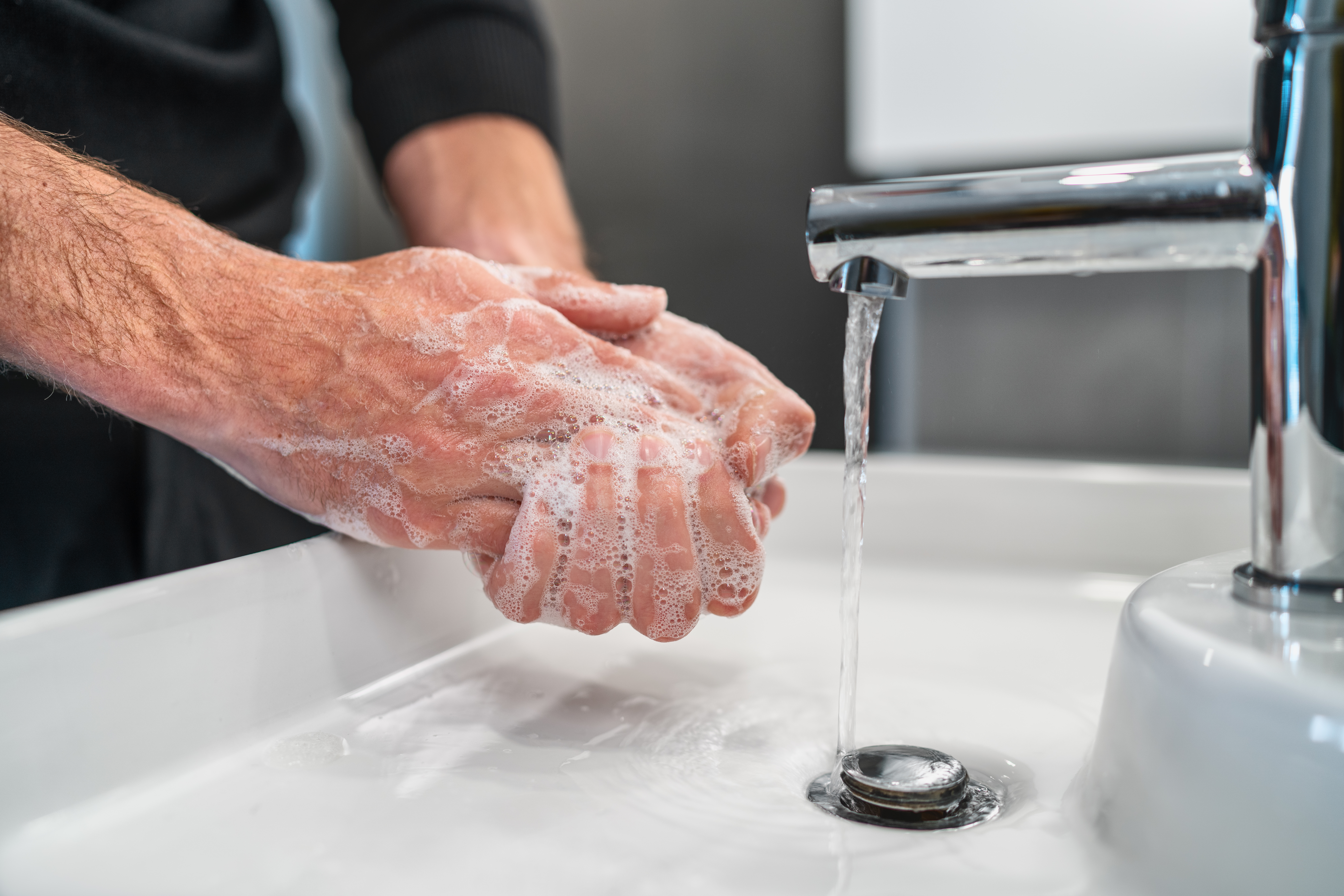 hands lathered in soap over a sink