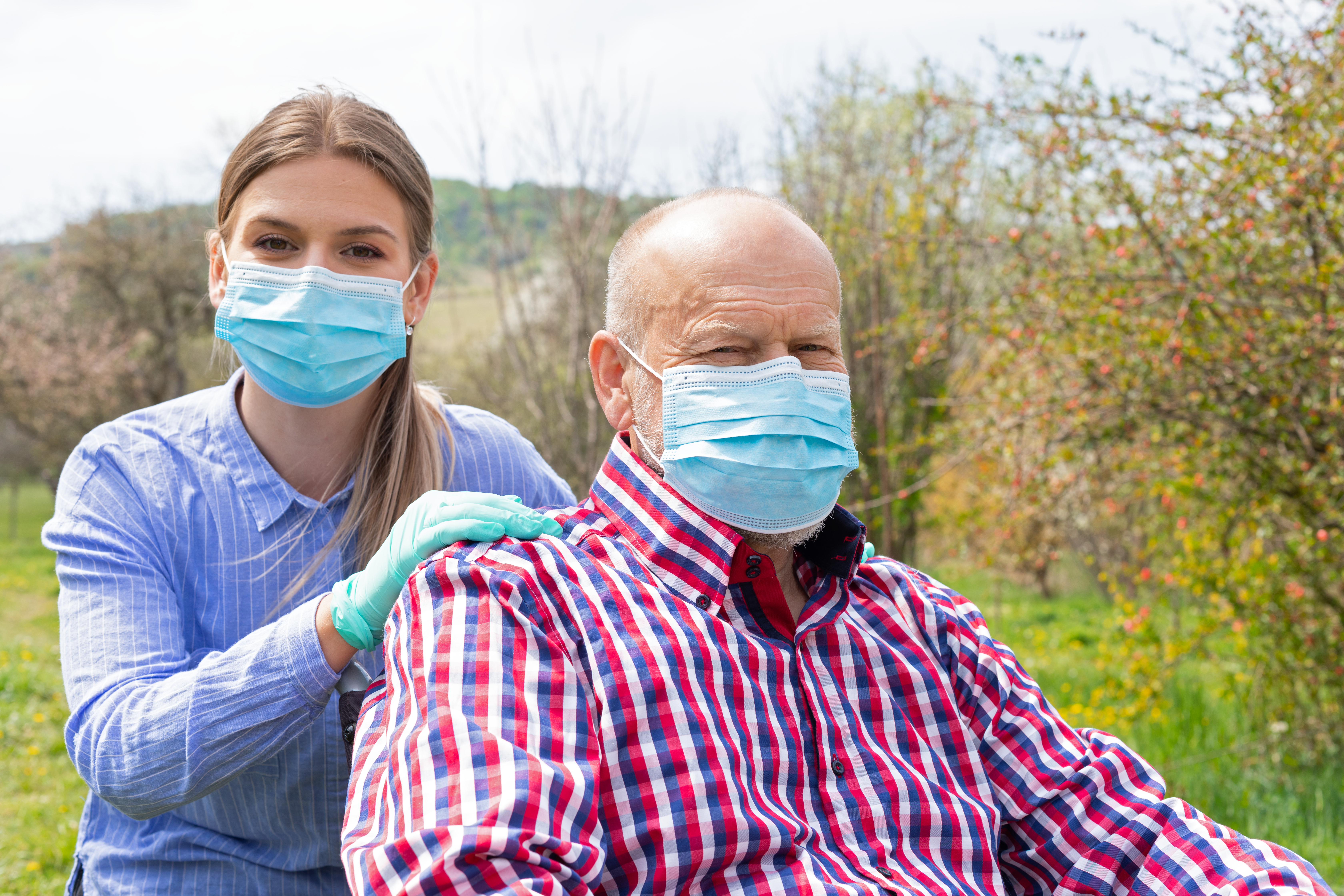 home care aide with patient, both wearing surgical masks
