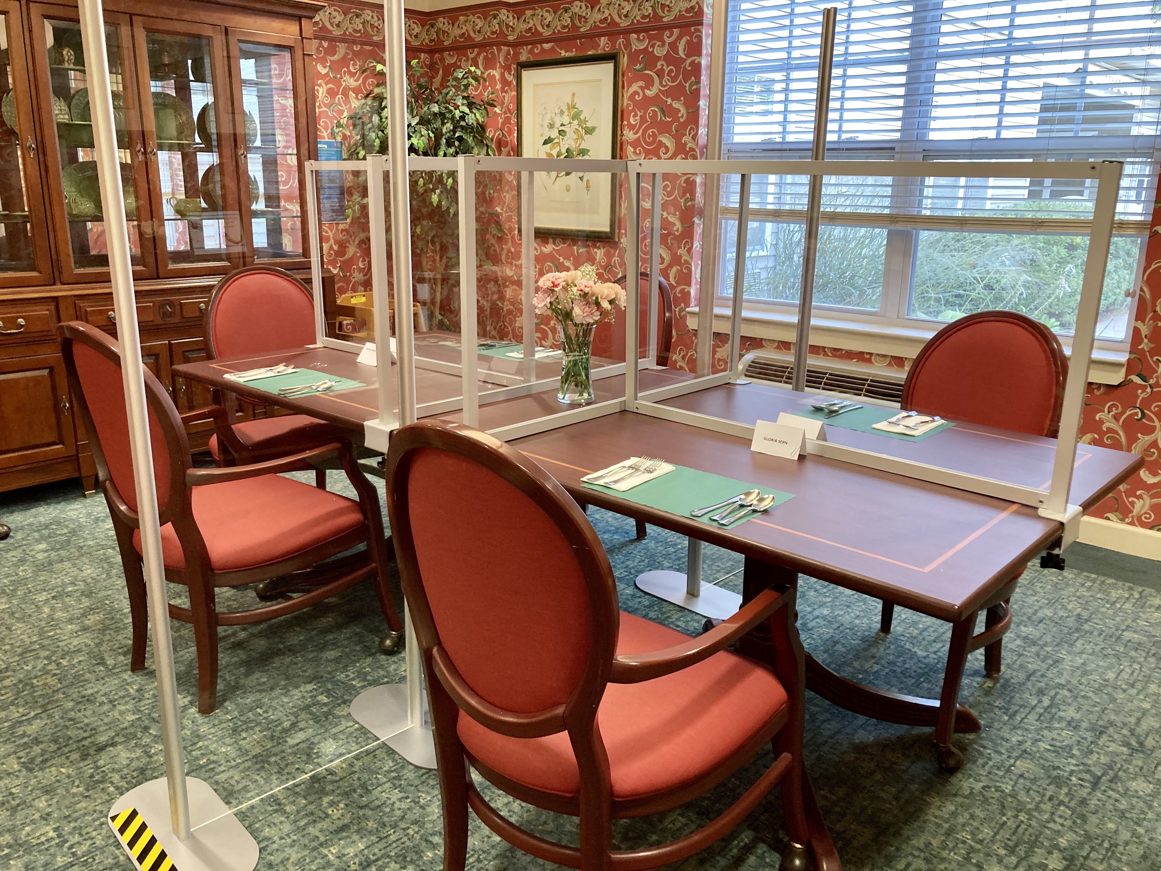 four chairs at a dining table, separated by plexiglass